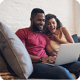 Casal sentado no sofá olhando para o computador